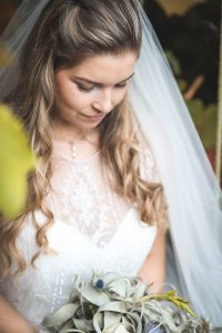 Bride looking at bouquet in the garden | Journey to the Centre of the Earth | modern ethereal winter styled bridal shoot by Hanami Dream | agate | marble | airplants | tulle | pale blue | gold | Oxleaze Barn | Gloucestershire | October 2017 | Photography by Squib Photography www.squibphotography.co.uk